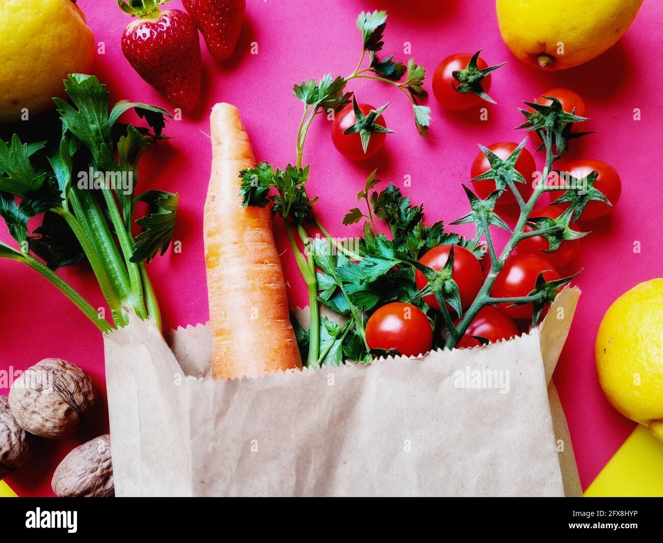 Top view of healthy vegetables and fruits in a paper bag on a pink ...