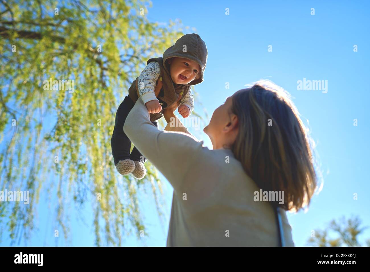 Silhouette of mother and baby at sunset. Mother throwing child up in