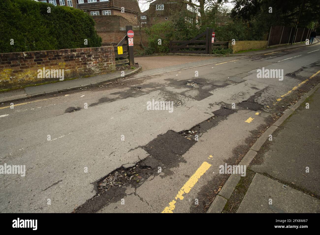 EPSOM, UK - CIRCA MARCH 2020: A road in bad condition with uneven surface and lots of potholes needing repair Stock Photo
