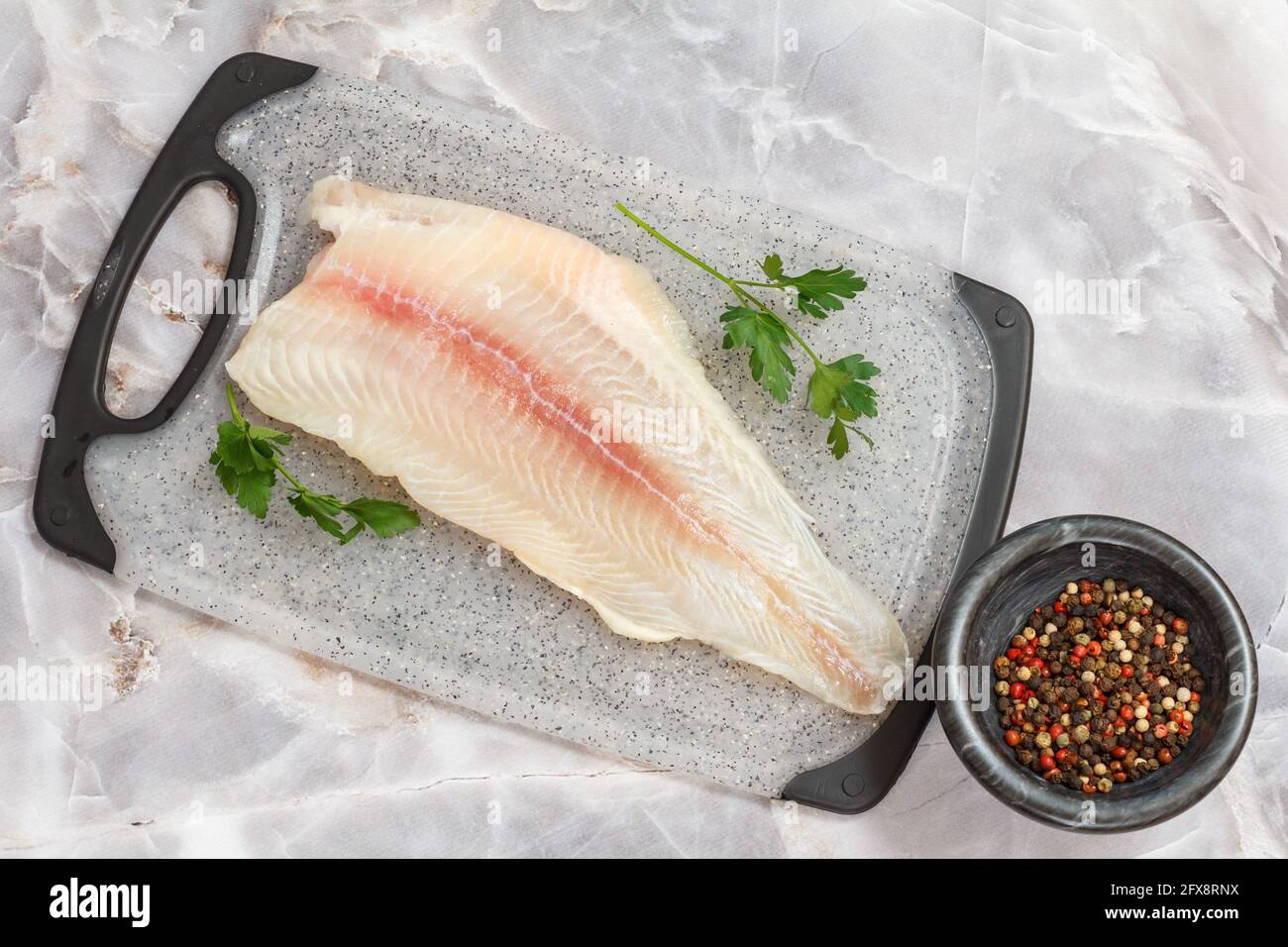 Fillet of raw pangasius fish with spices on cutting board Stock Photo
