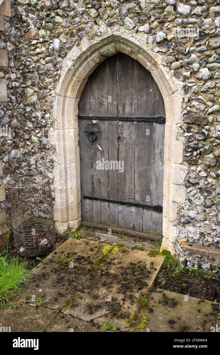 An old Oak arched door with long bolted hinges in a stone wall at a church in mid Norfolk England Stock Photo