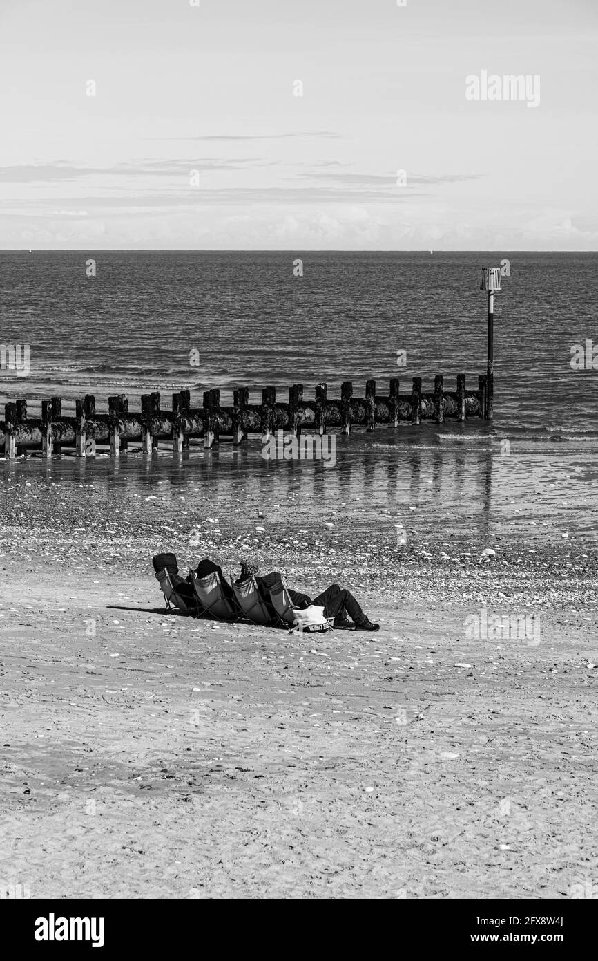 Four people sunbathing in the middle of April beside the North Sea at Bridlington, East Riding of Yorkshire, England UK. Colour version 2FX8W58. Stock Photo