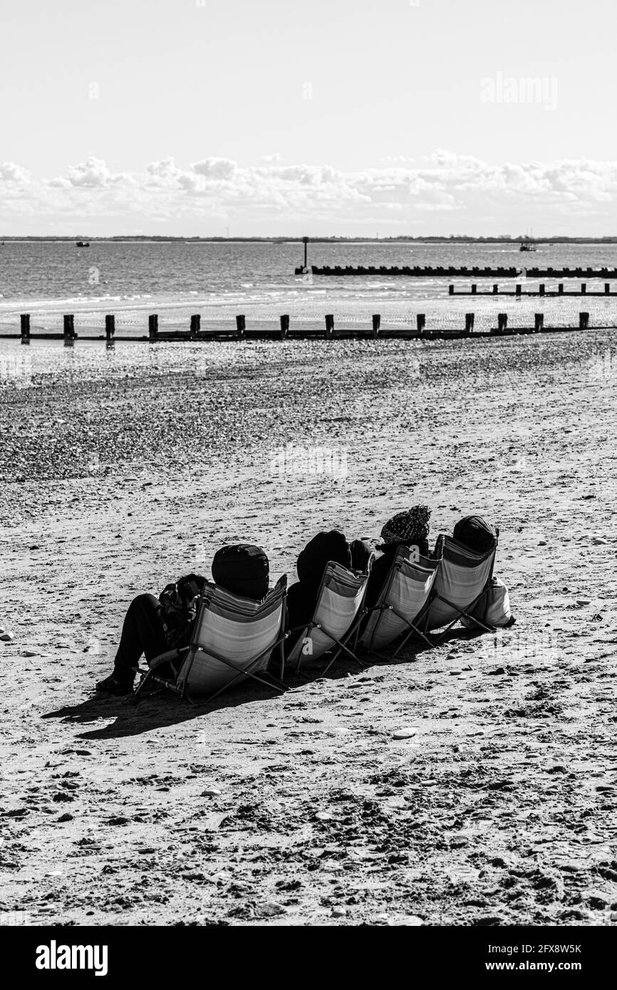 Four people sunbathing in the middle of April beside the North Sea at Bridlington, East Riding of Yorkshire, England UK. Colour version 2FX8W9J. Stock Photo