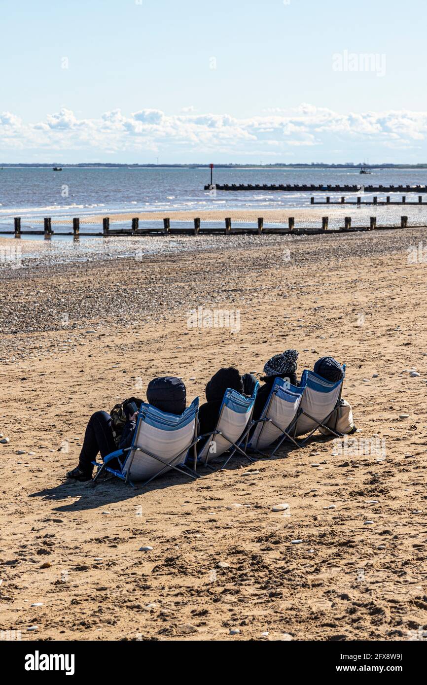 Four people sunbathing in the middle of April beside the North Sea at Bridlington, East Riding of Yorkshire, England UK. Black & white version 2FX8W5K Stock Photo