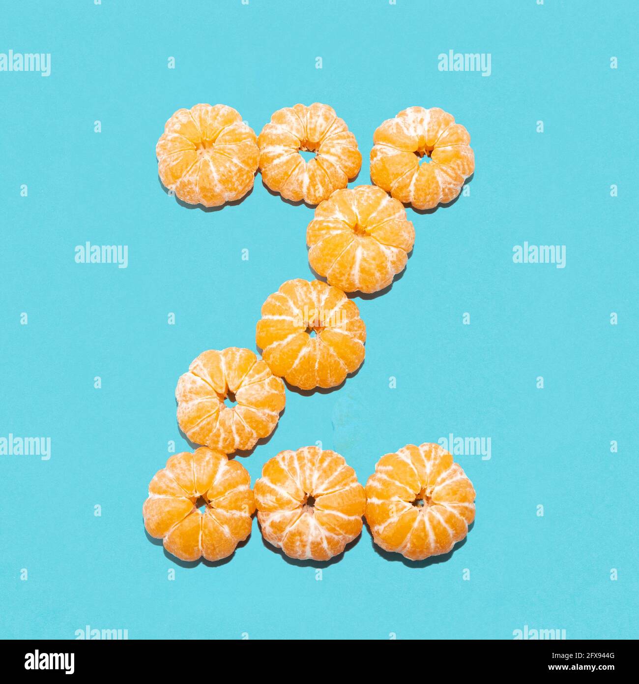 Creative layout of the letter Z from peeled tangerines on a blue background. Flatlay. Stock Photo