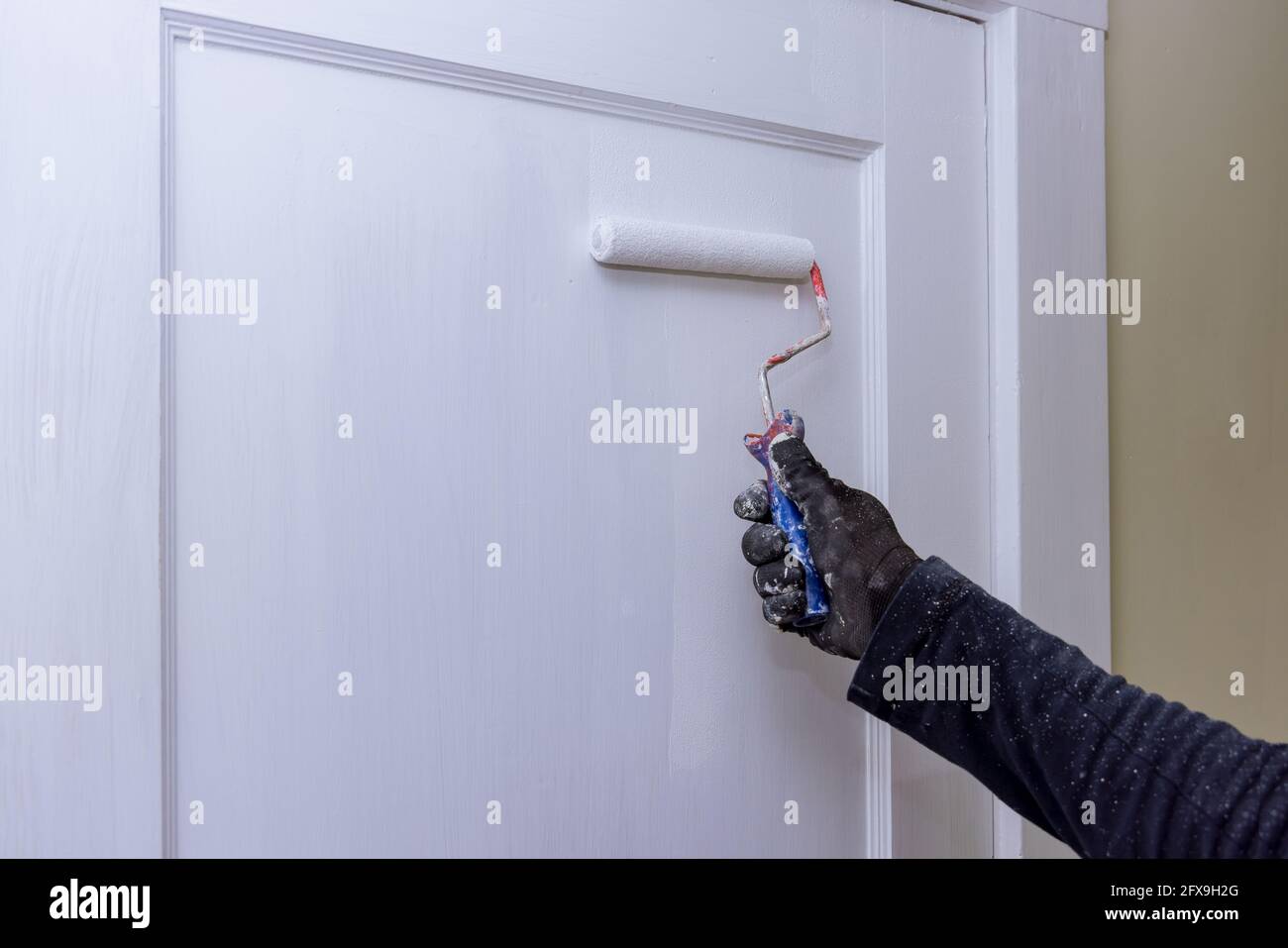 Close up of painter hands with gloves painting the door frame using