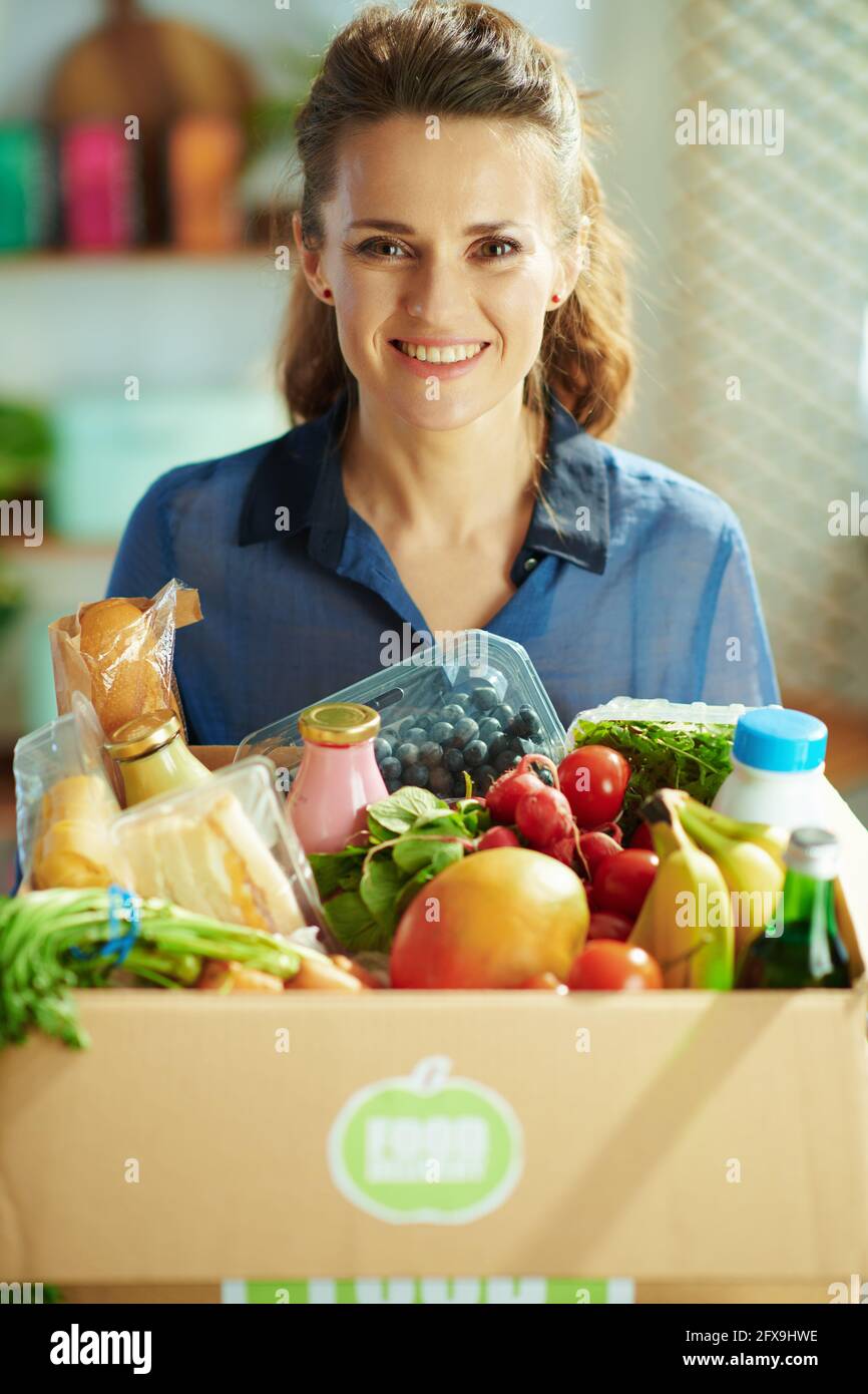 Food delivery. happy middle aged housewife with food box in the kitchen