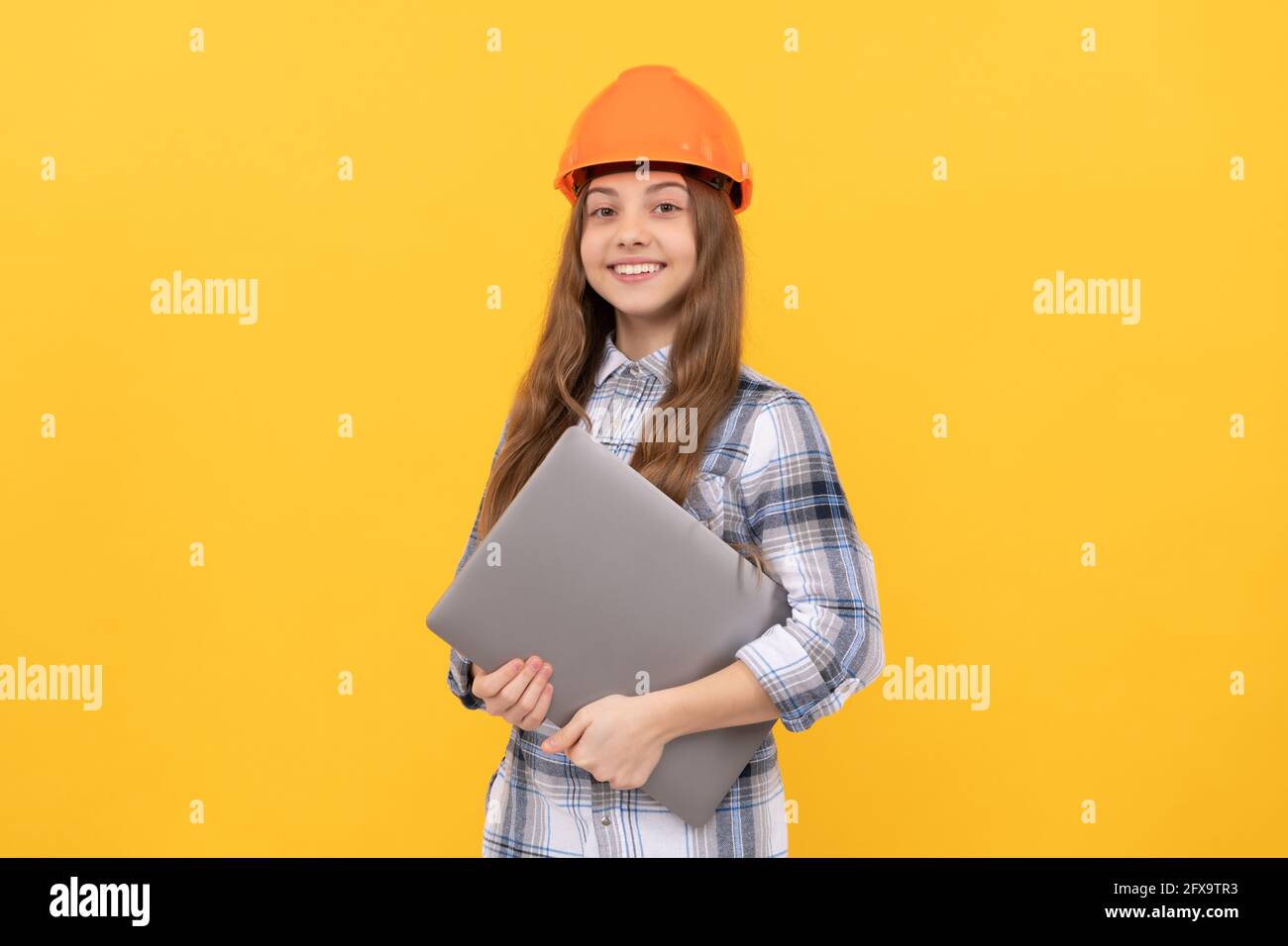 happy teen girl in helmet and checkered shirt holding laptop, online courses Stock Photo