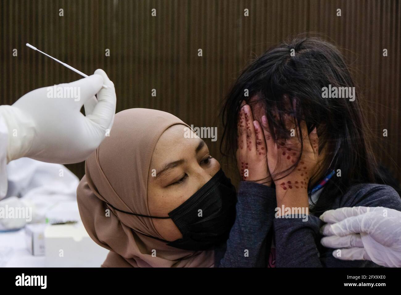 Sungai Buloh, Malaysia. 26th May, 2021. A mother talks to her child to take the nasal swab sample during the COVID19 testing at a test center in Sungai Buloh. Malaysia has recorded the highest daily cases of Covid-19, yesterday with a record of 7,289 cases. Selangor government continues to conduct mass COVID19 screening tests over the state to battle the coronavirus pandemic. (Photo by Faris Hadziq/SOPA Images/Sipa USA) Credit: Sipa USA/Alamy Live News Stock Photo