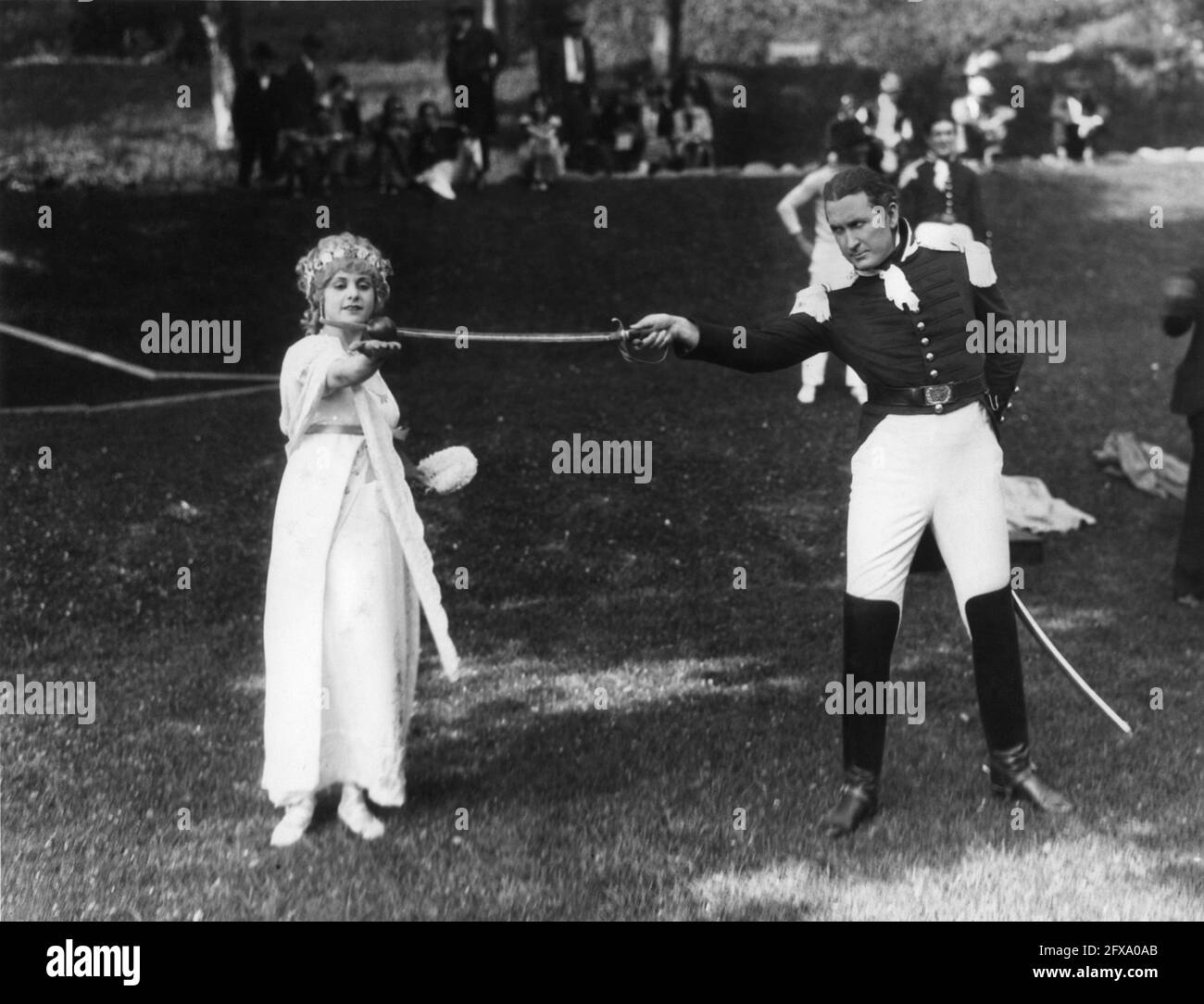 TIM McCOY demonstrating his skills with a sabre to LOUISE LORRAINE on set candid during filming of THE FRONTIERSMAN 1927 director REGINALD BARKER cinematographer Clyde De Vinna costume design Andre-ani Metro Goldwyn Mayer Stock Photo