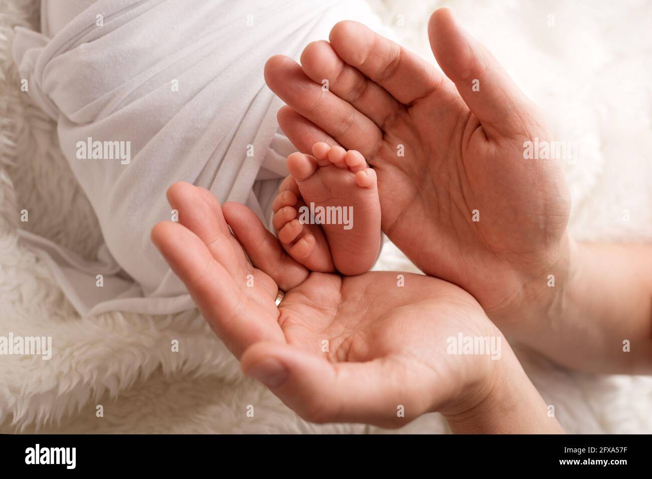 Children's feet in hold hands of mother and father. Mother, father and Child. Happy Family people concept. Stock Photo