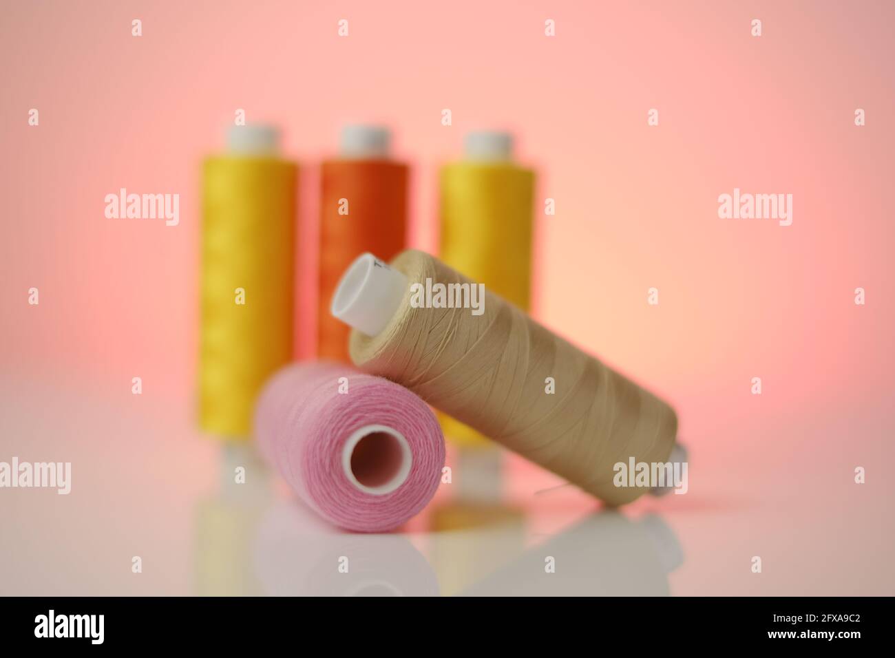 Sewing threads.Multicolored threads . Yellow, orange and pink threads ...