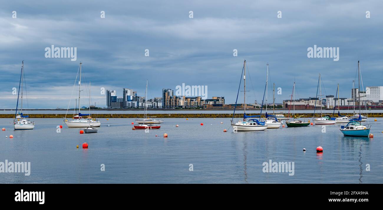 Edinburgh, Scotland, United Kingdom, 26th May 2021. Sailing boats moored in Granton harbour with Platinum Point modern apartment blocks in the distance Stock Photo