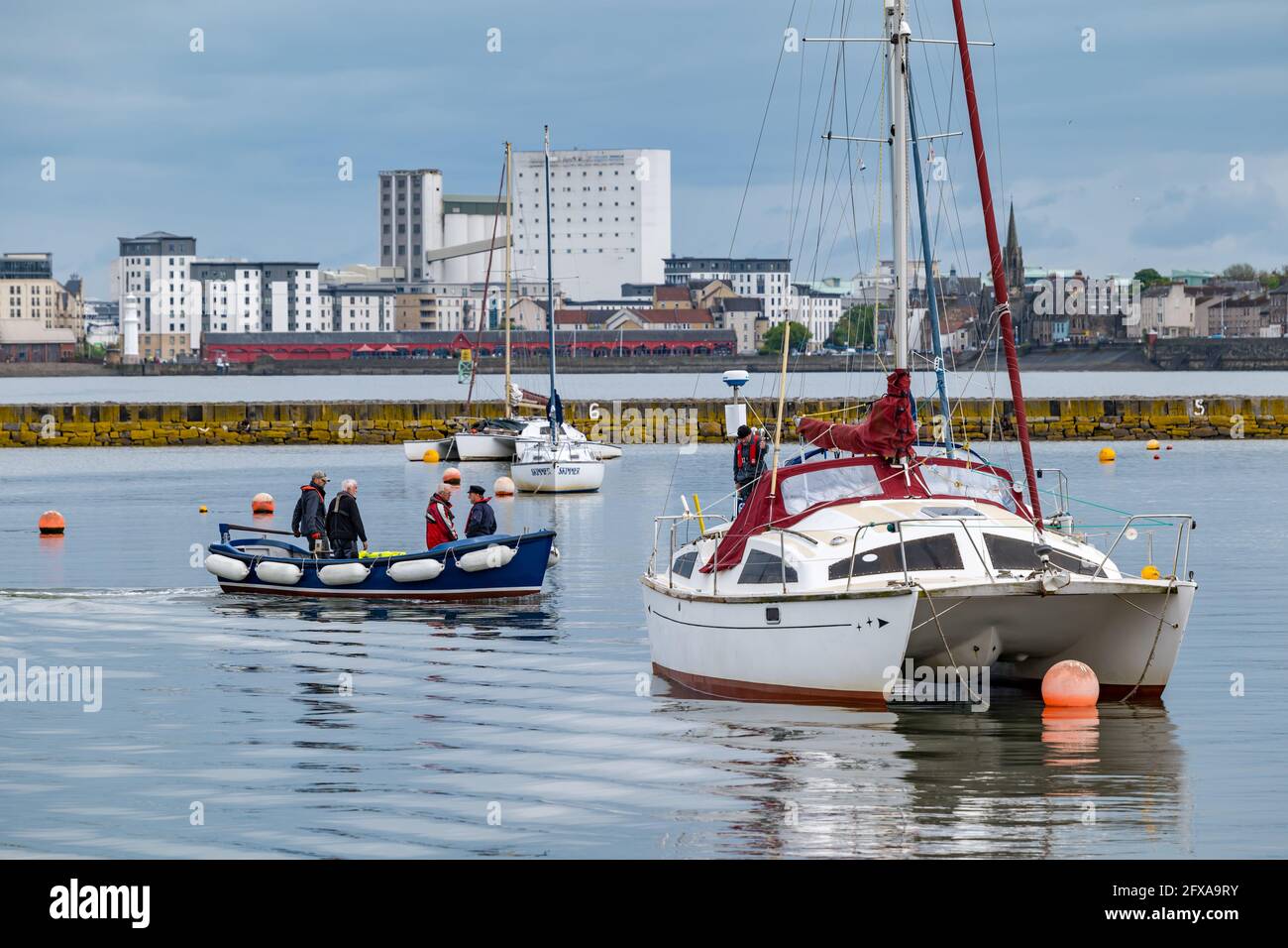 Edinburgh, Scotland, United Kingdom, 26th May 2021. Catamaran sailing boats moored in Granton harbour with Platinum Point apartment blocks in the distance Stock Photo