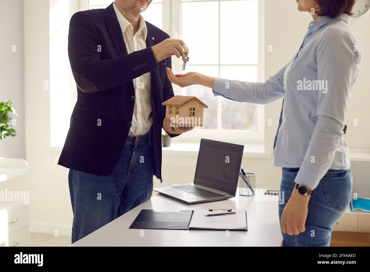 Hand of real estate agent passes key to new homeowner while buyer sign contract Stock Photo
