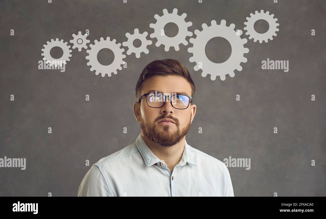 Young businessman thinking about project optimization standing on a gray background. Stock Photo
