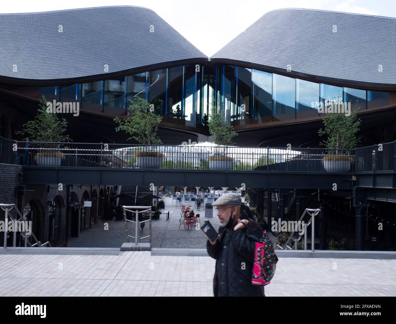 Male talking on phone passing KIngs Cross London, Samsung KX building Coal Drops Yard, concept store Stock Photo