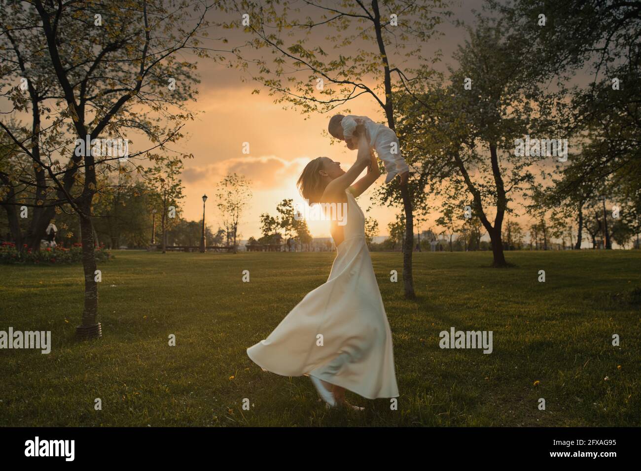 Happy harmonious family outdoors. mother throws baby up, laughing and