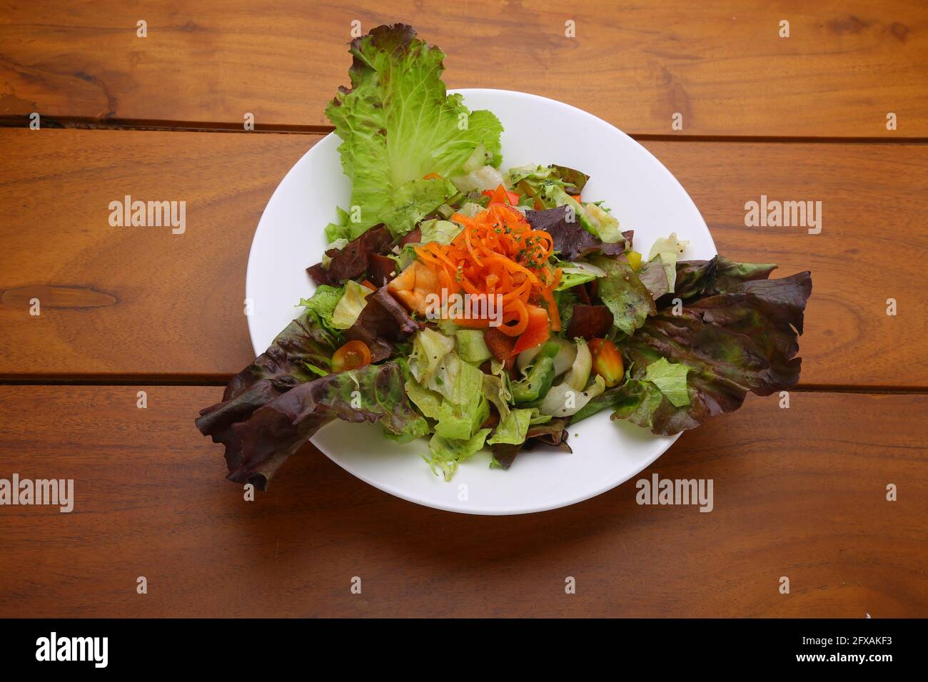 Dark Leafy Green Veg Salad,healthy leafy salad arranged beautifully in a white plate with wooden background Stock Photo