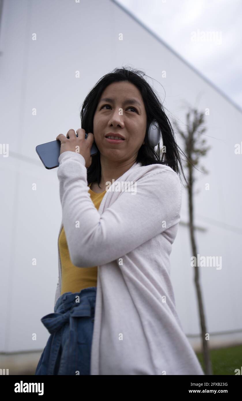 Young Hispanic female listening to music on her headphones Stock Photo ...