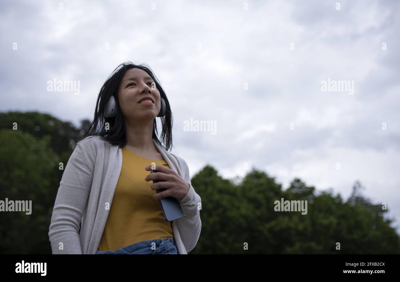 Young Hispanic female listening to music on her headphones and smiling ...