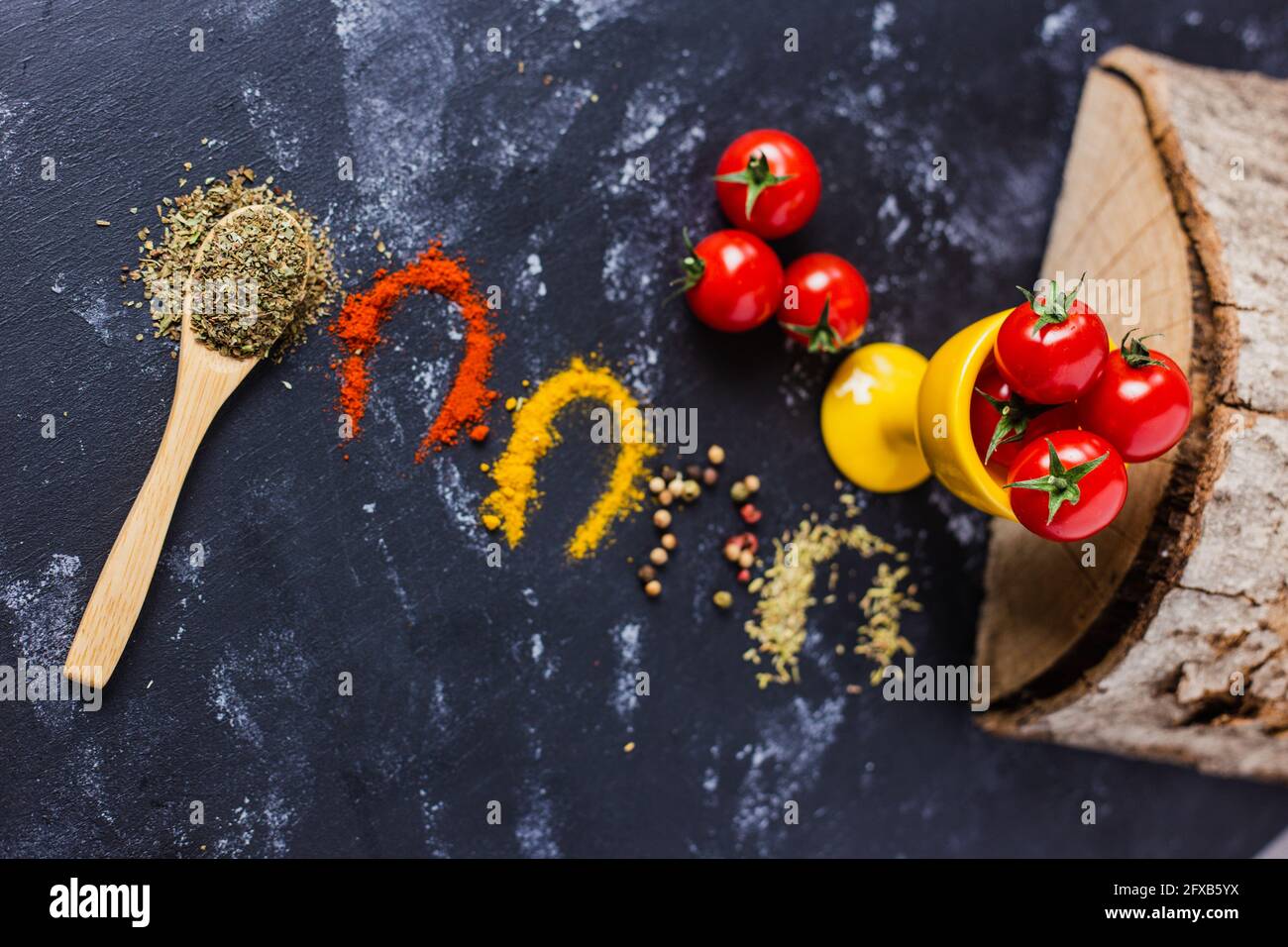 Spoon and spices with cherry tomatoes on a dark table Stock Photo