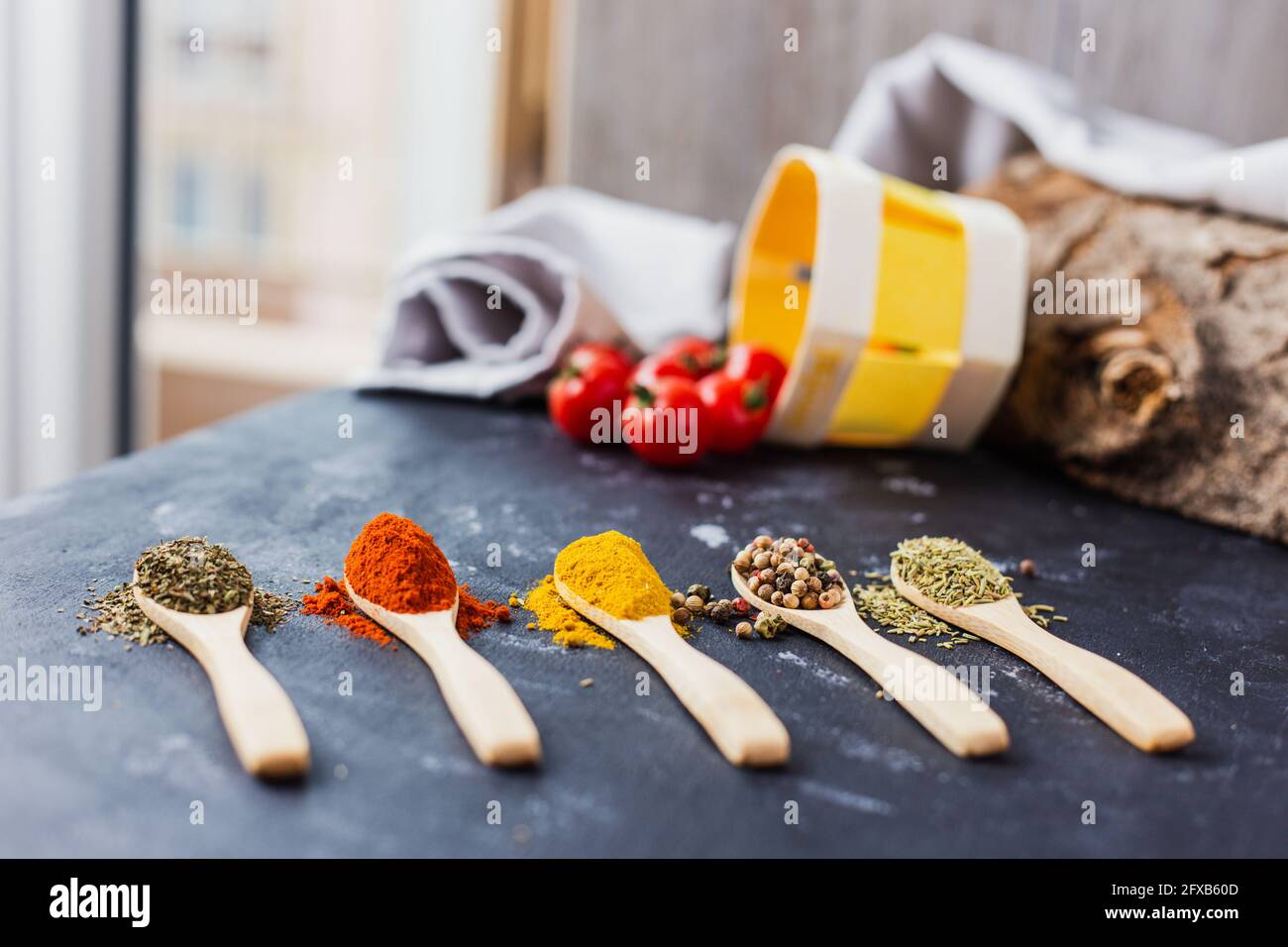 Wooden spoons with spices, paprika, basilic, pepper, thyme with cherry tomatoes Stock Photo