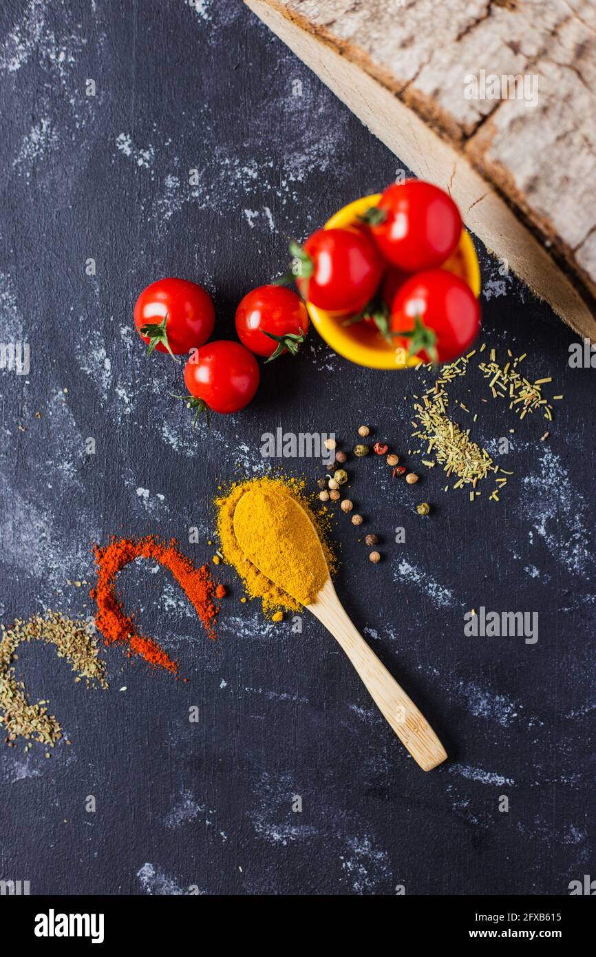 Spoon and spices with cherry tomatoes on a dark table Stock Photo