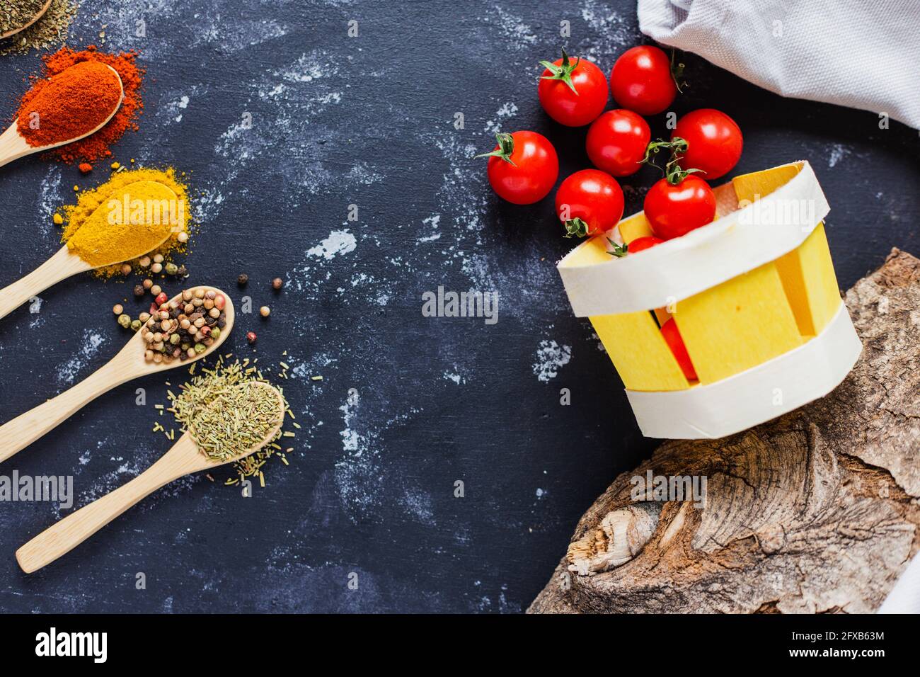 Wooden spoons with spices, paprika, basilic, pepper, thyme with cherry tomatoes Stock Photo