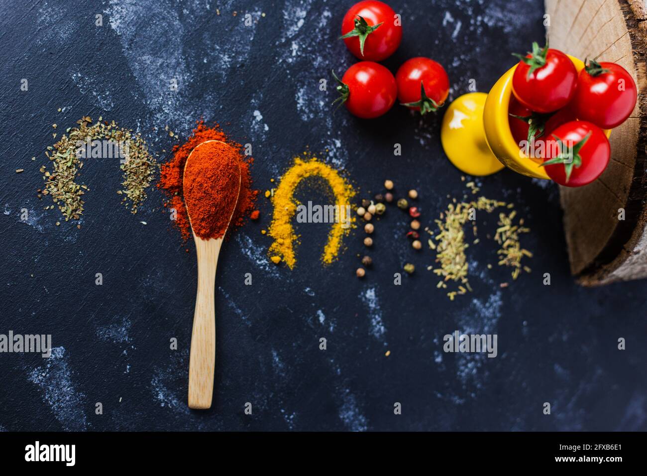 Spoon and spices with cherry tomatoes on a dark table Stock Photo