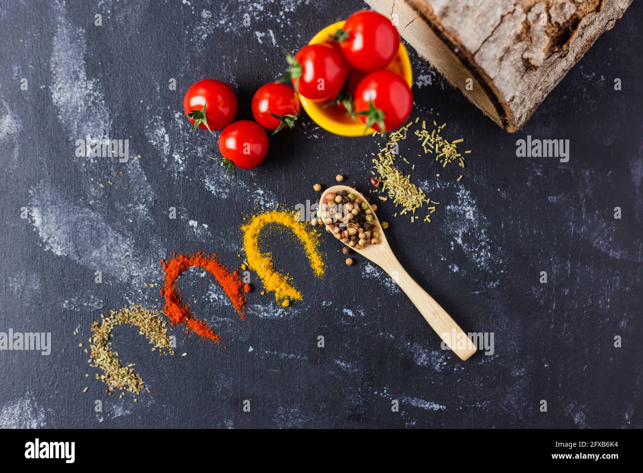 Spoon and spices with cherry tomatoes on a dark table Stock Photo