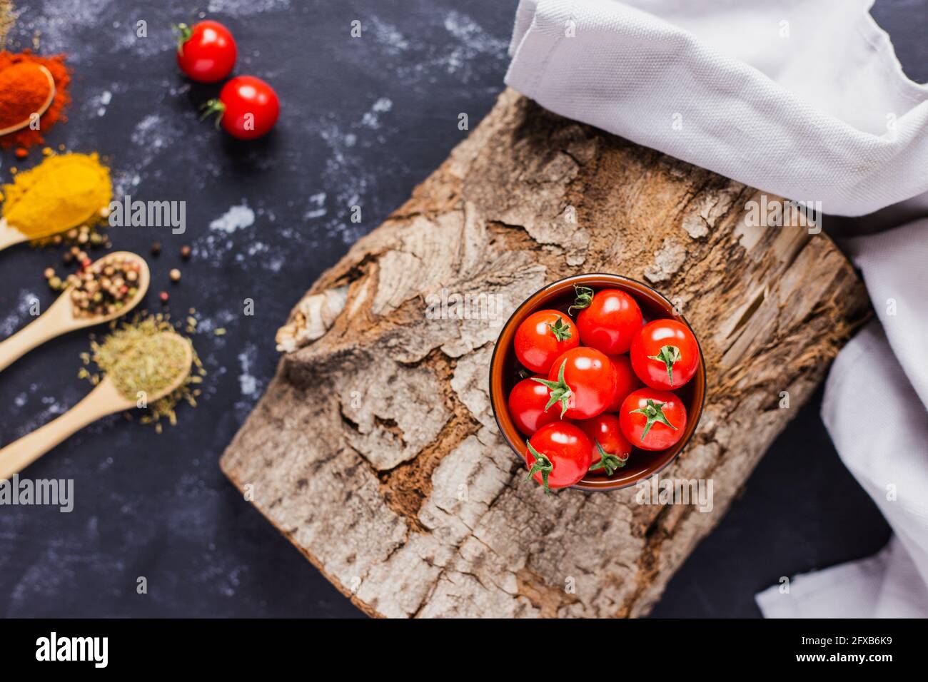Wooden spoons with spices, paprika, basilic, pepper, thyme with cherry tomatoes Stock Photo