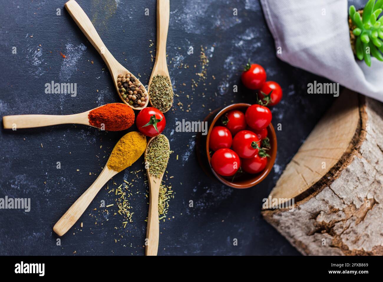 Wooden spoons with spices, paprika, basilic, pepper, thyme with cherry tomatoes Stock Photo