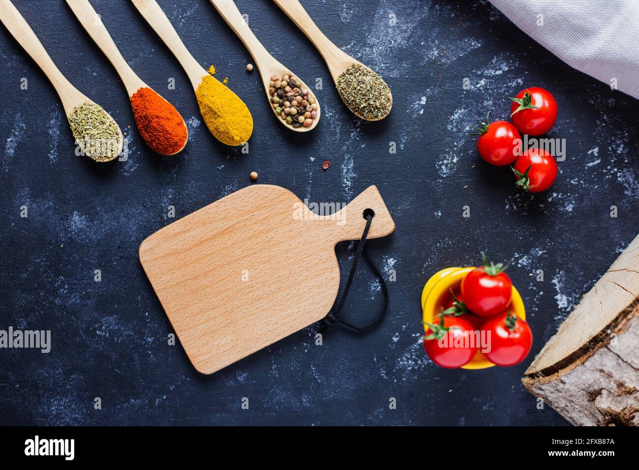 Wooden spoons with spices, paprika, basilic, pepper, thyme with cherry tomatoes Stock Photo