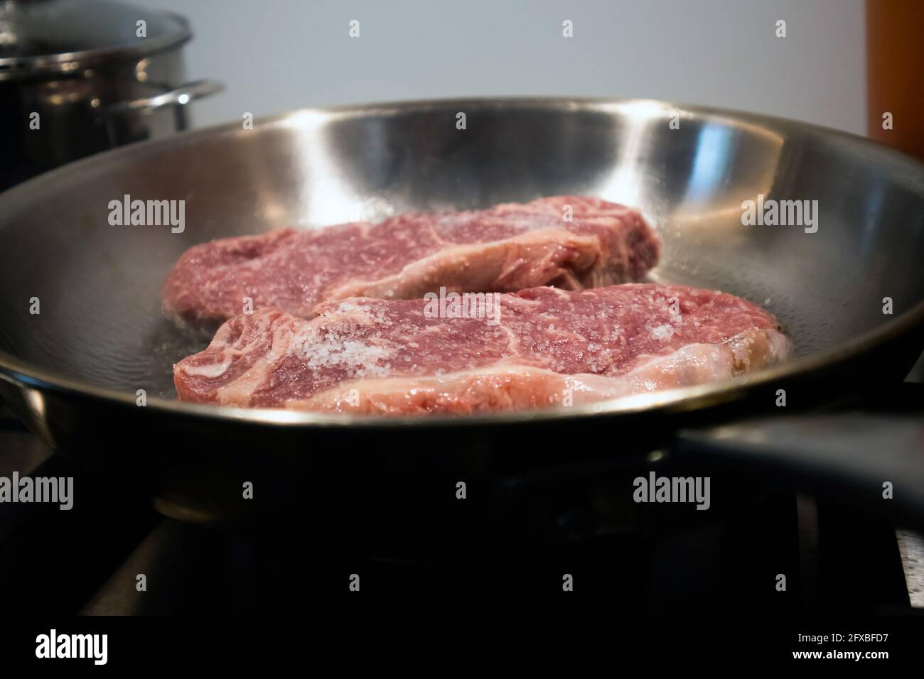 Searing beef steak in a stainless steel pan Stock Photo Alamy