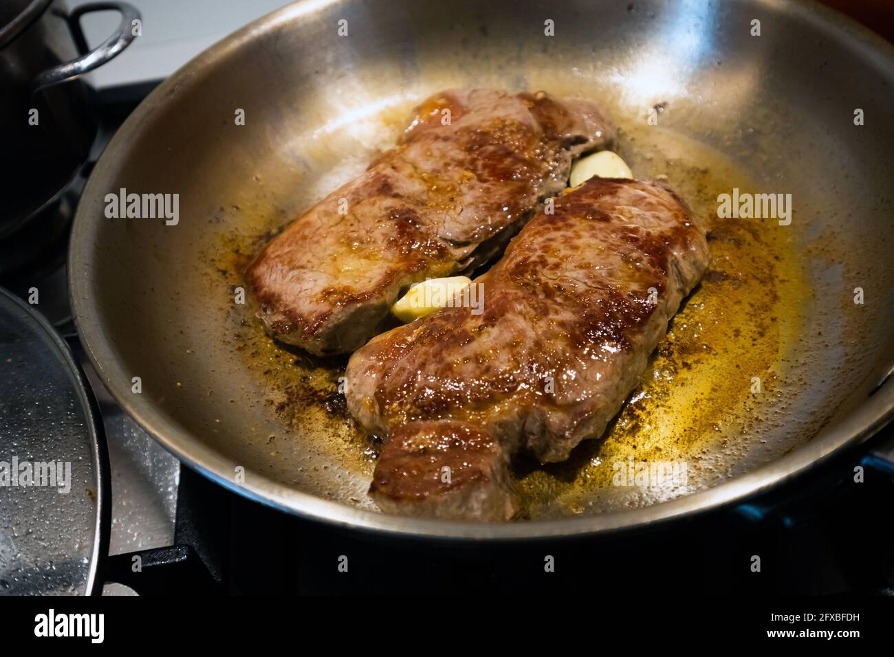 Searing beef steak in a stainless steel pan Stock Photo Alamy