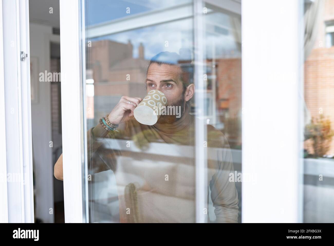 Man having coffee while looking through window seen through glass Stock Photo