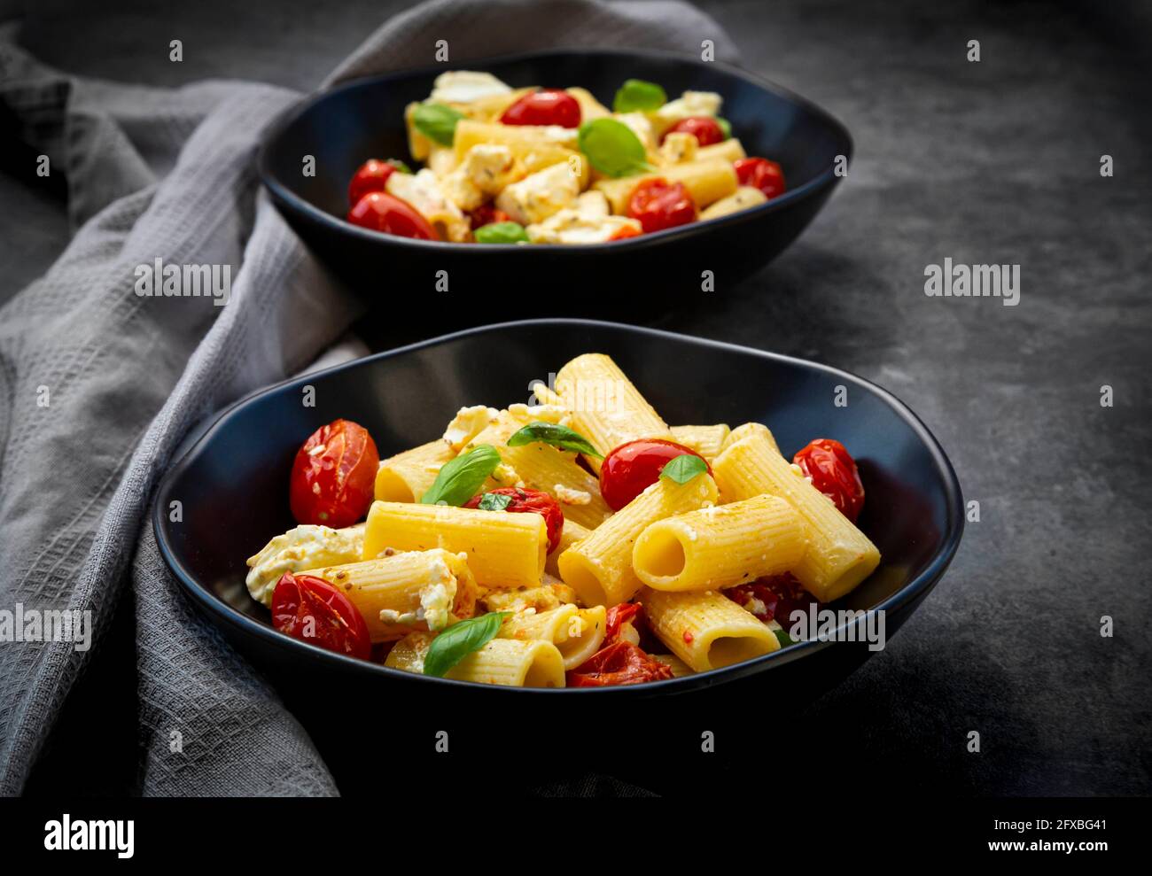 Rigatoni pasta with baked tomatoes, feta and basil Stock Photo