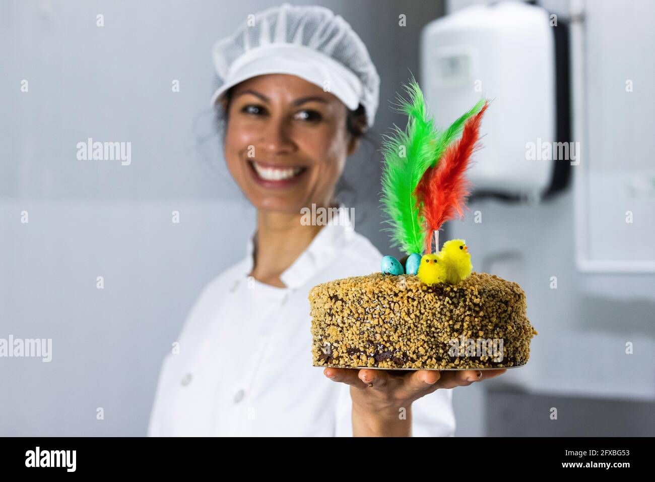 https://c8.alamy.com/comp/2FXBG53/female-chef-holding-cake-with-feathers-in-kitchen-2FXBG53.jpg