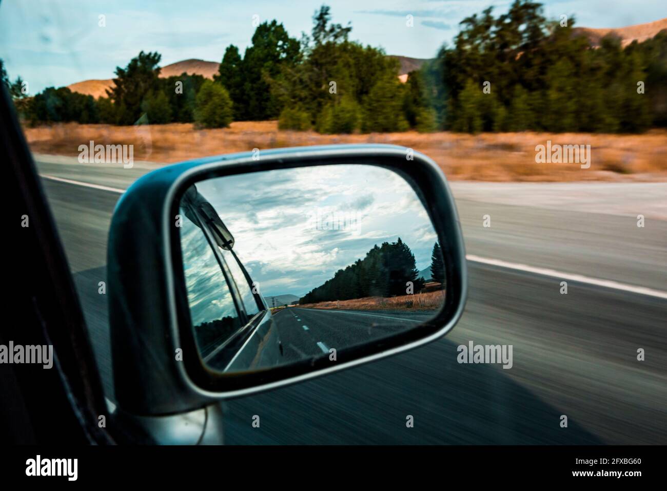 Side-view mirror reflection of car driving along State Highway 8 Stock Photo