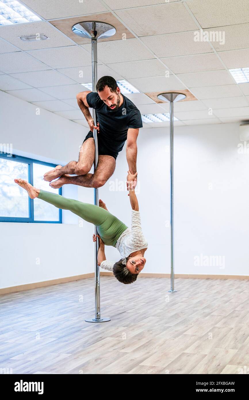 Multi-ethnic male and female acrobats practicing together on rod in ...