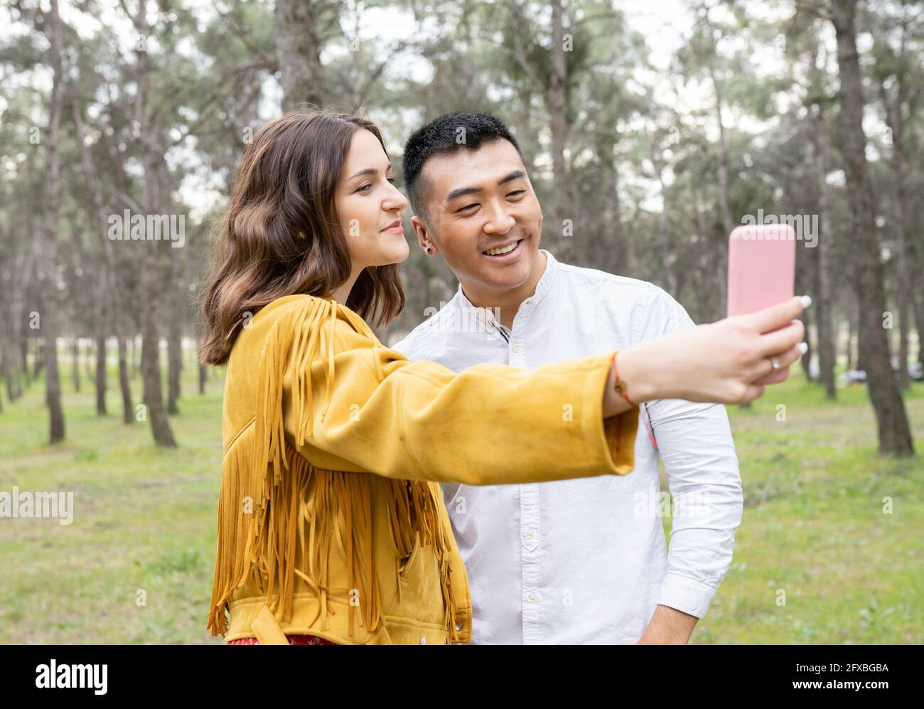 Man with beautiful woman taking selfie on smart phone at forest Stock Photo