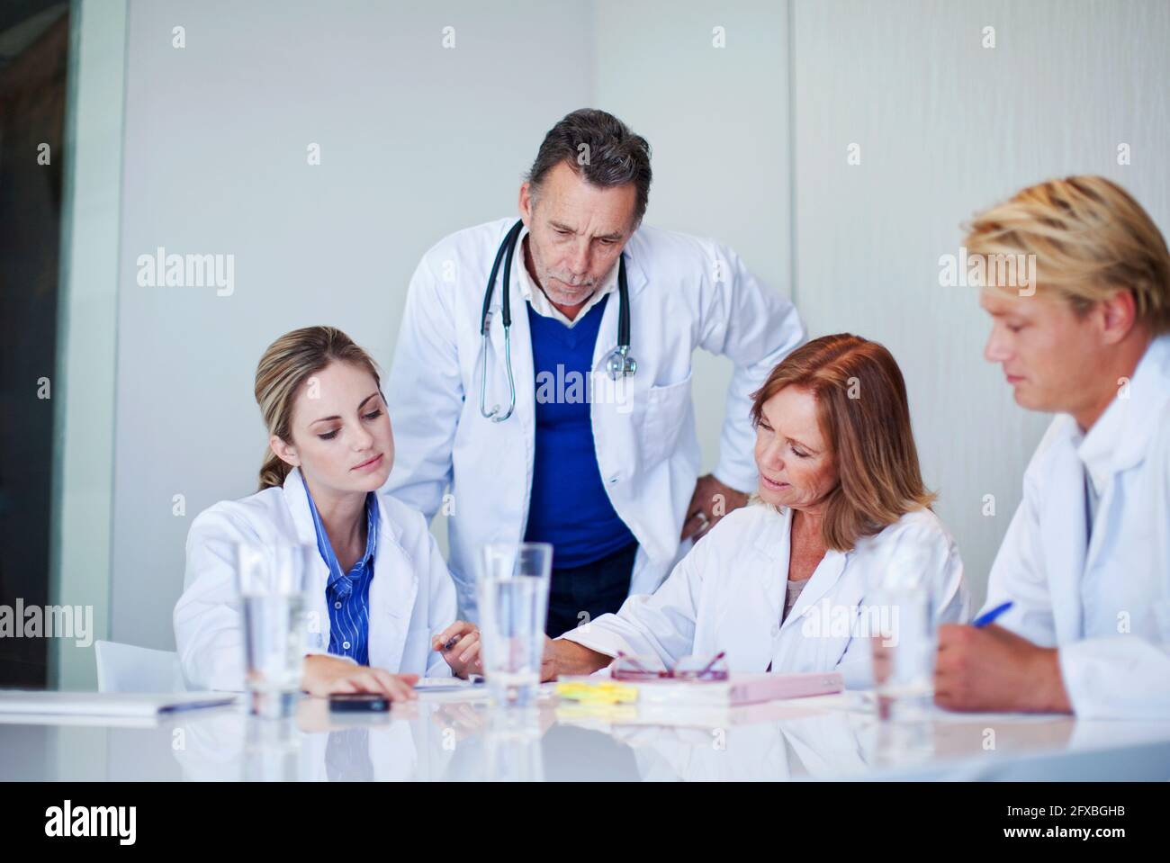 Mature female doctor assessing healthcare workers in meeting at hospital Stock Photo