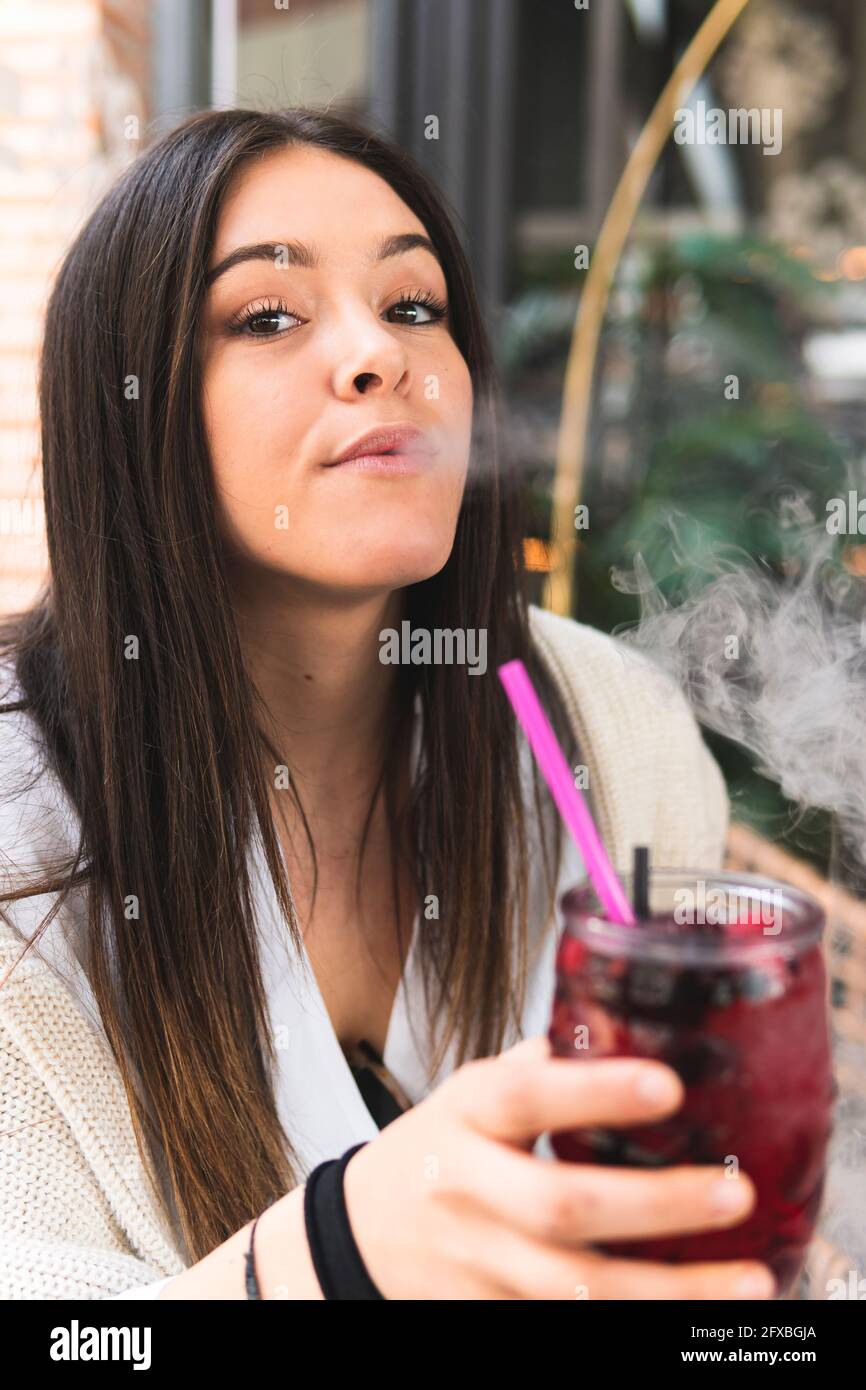 Beautiful woman smoking while having cocktail in bar Stock Photo