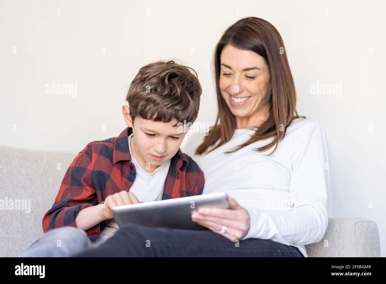 Boy using digital tablet by mother at home Stock Photo Alamy