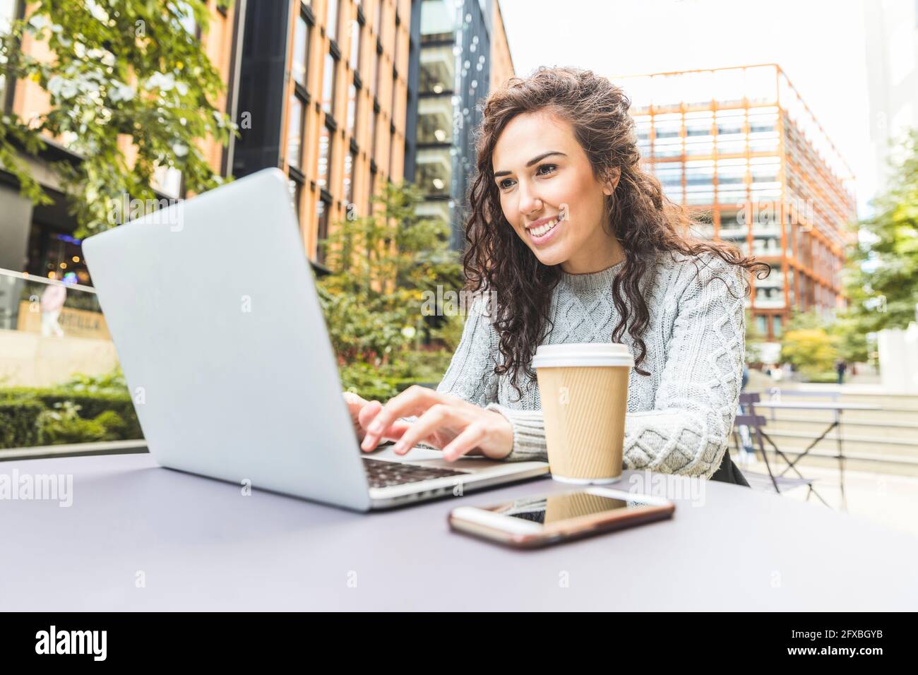 Smiling businesswoman using laptop at cafe in city Stock Photo