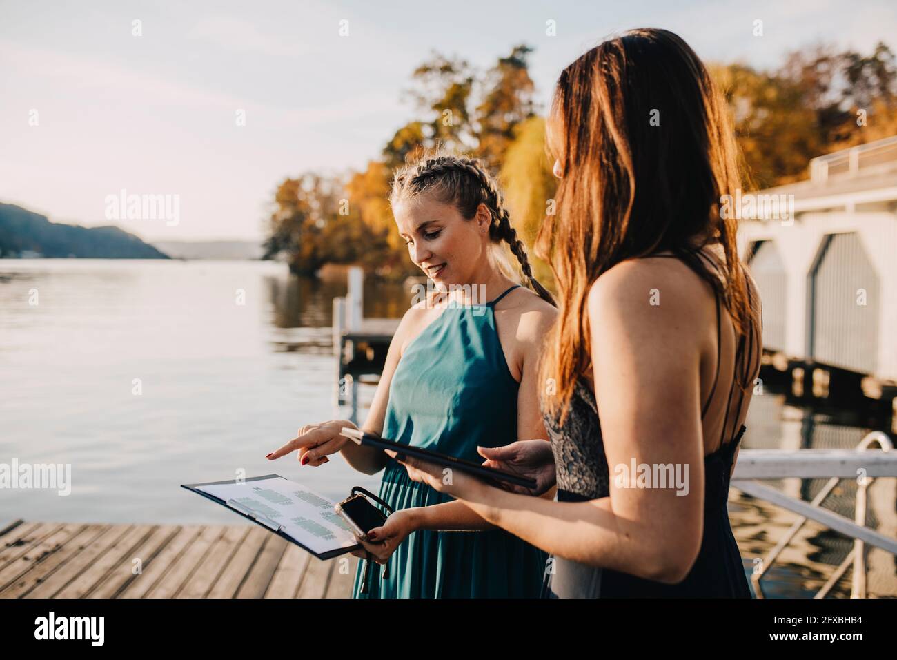 Female planners discussing over clipboard near lake Stock Photo