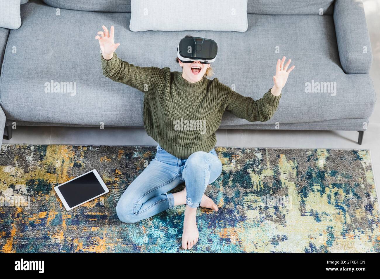 Cheerful woman gesturing while using virtual reality headset at home ...