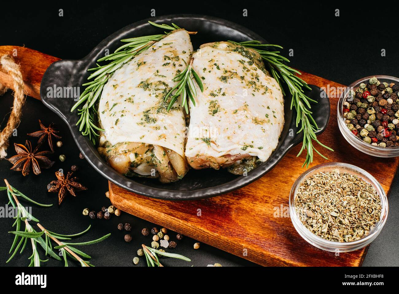 Raw chicken thighs in white marinade with fresh rosemary spices. Meat