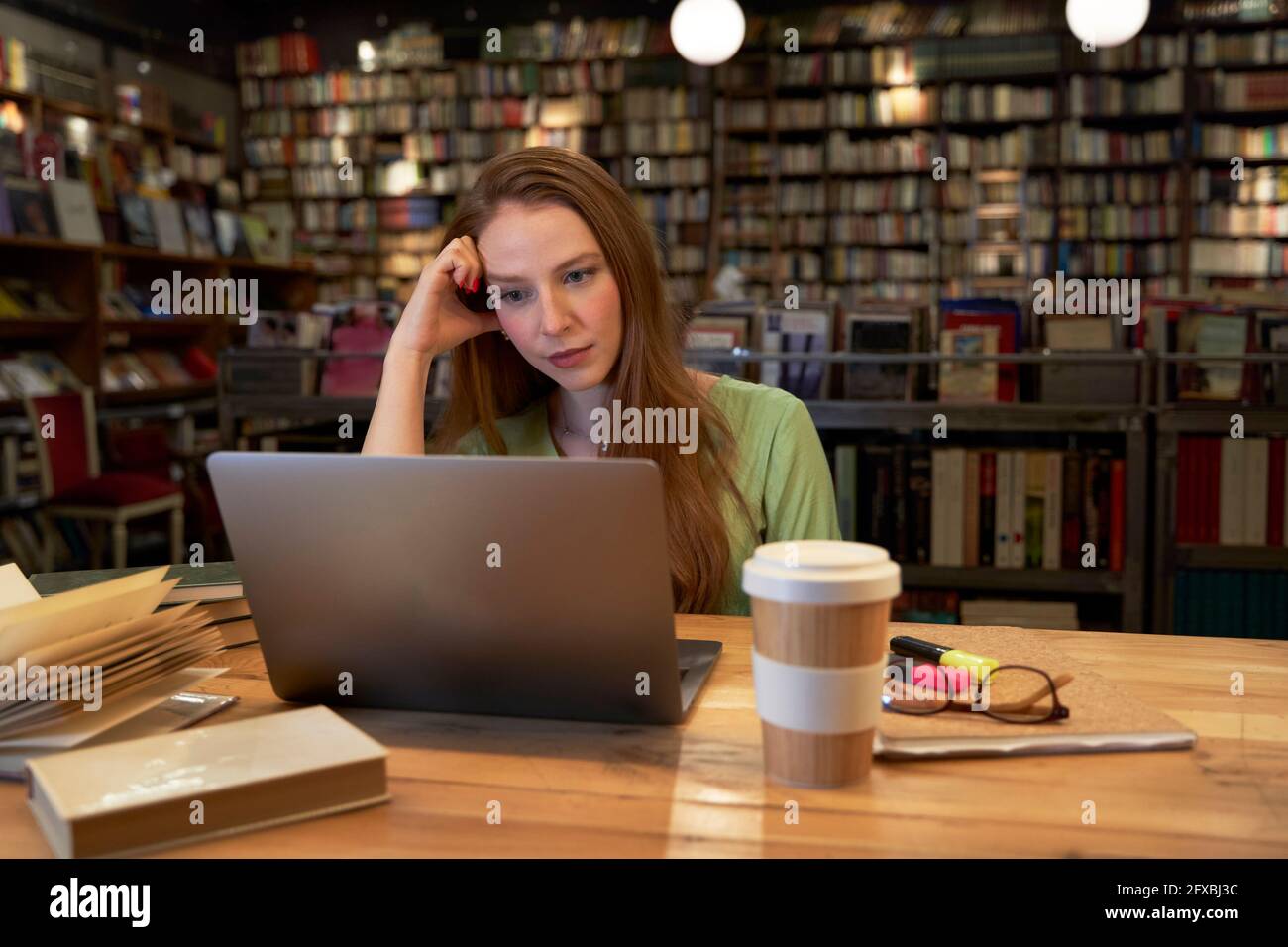 Young woman studying through laptop in library Stock Photo